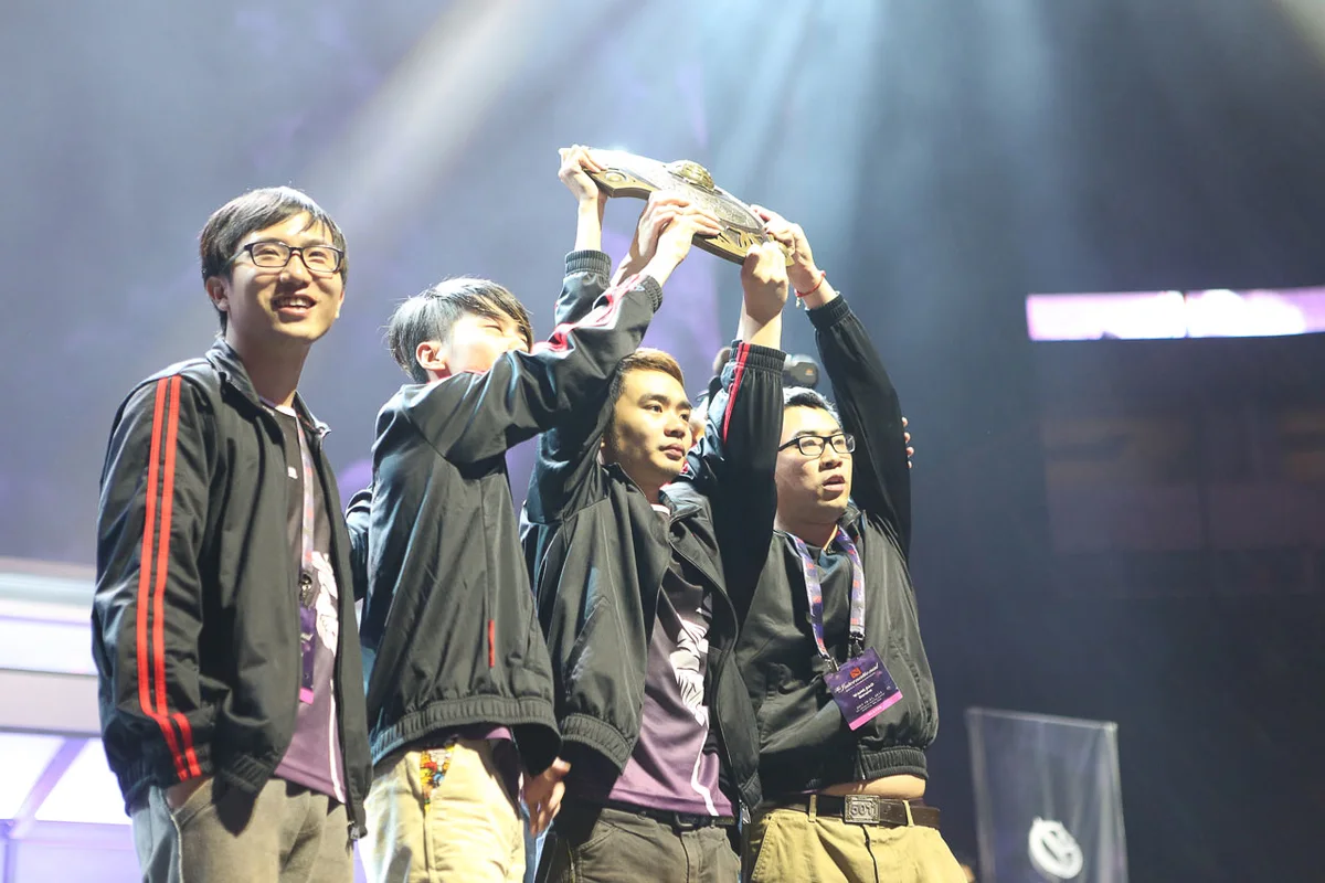 Newbee players lift the physical Aegis trophy on stage at The International 2014